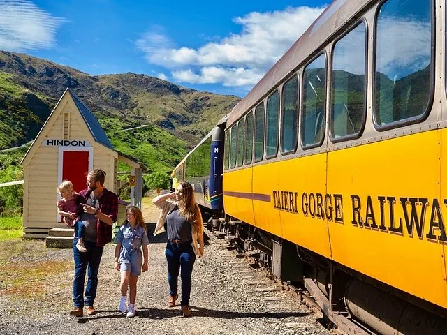Family walking beside the yellow Taieri Gorge Railway train at Hindon station