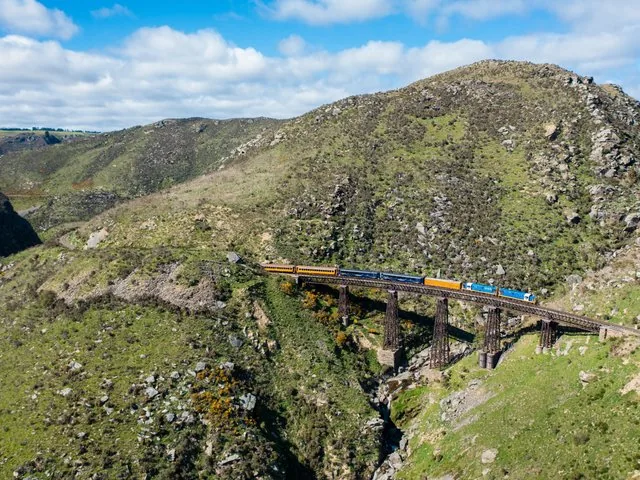 Aerial view of a train crossing a high trestle bridge in a gorge