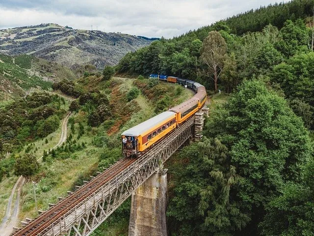 Train crossing a long trestle bridge over a deep, forested gorge