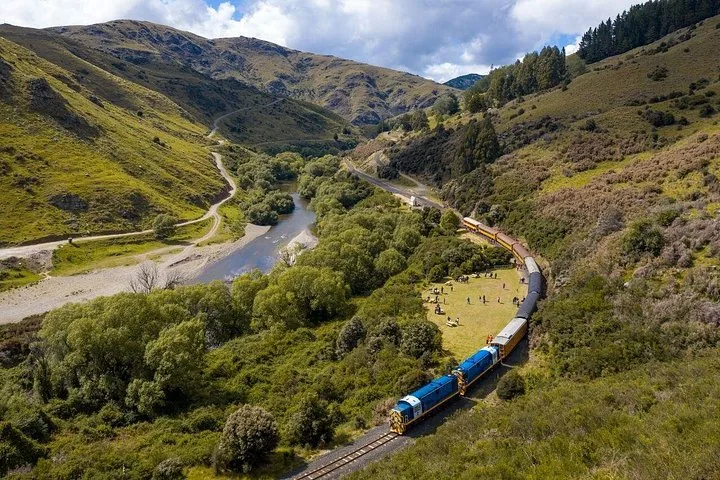 Aerial view of the train moving through a lush, green river valley
