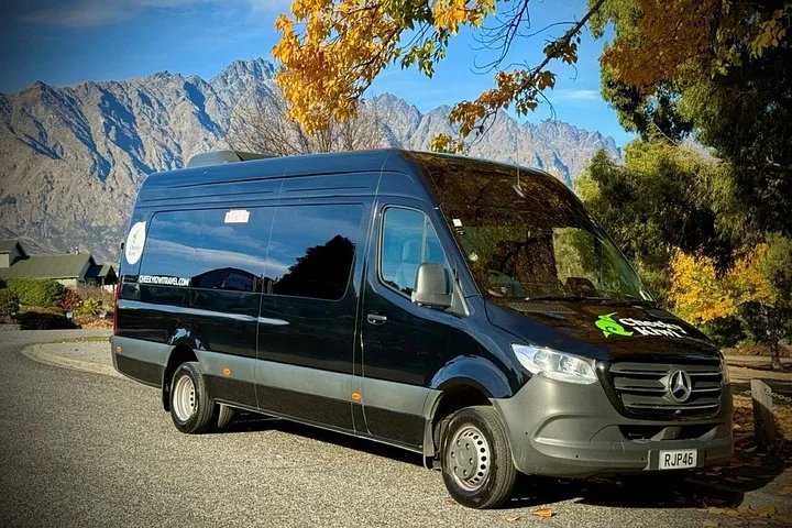 Black Cheeky Kiwi Travel tour van parked with mountain backdrop in autumn